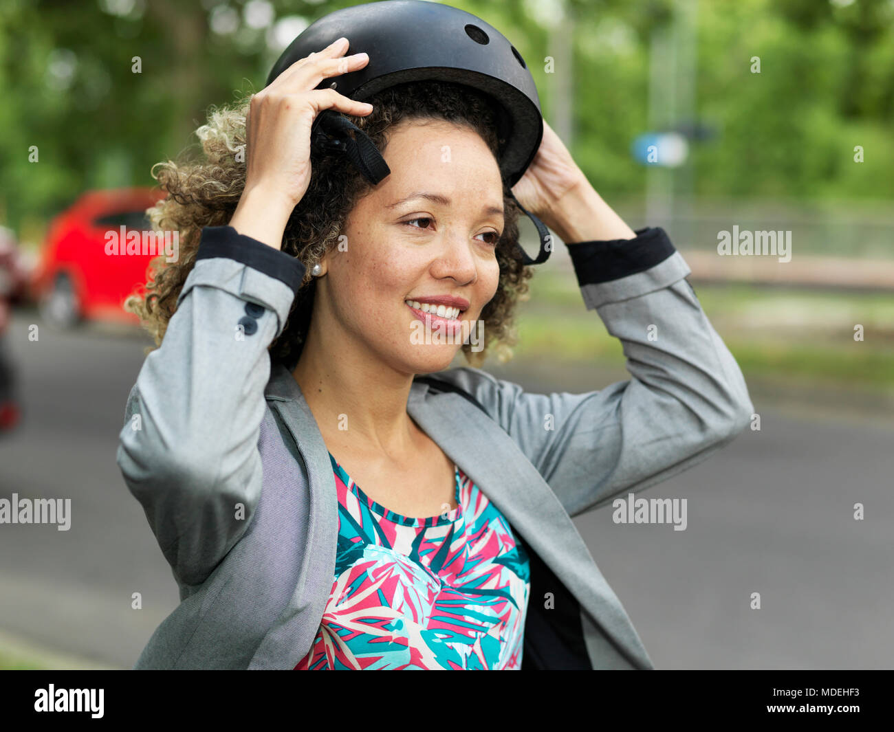 Mid adult woman putting on bicycle safety helmet Stock Photo