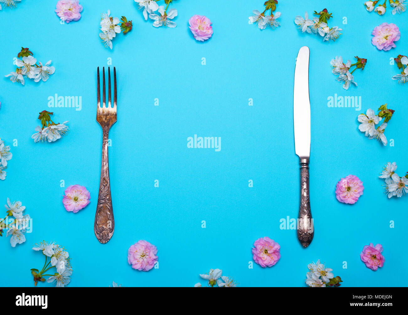 vintage fork and knife on a blue background with flowering pink and