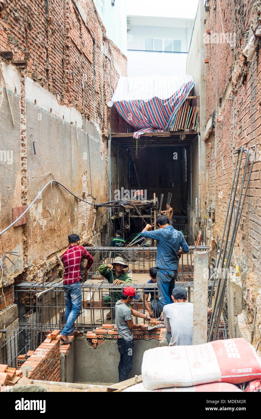 Vietnamese workmen on a small construction site laying bricks a doing