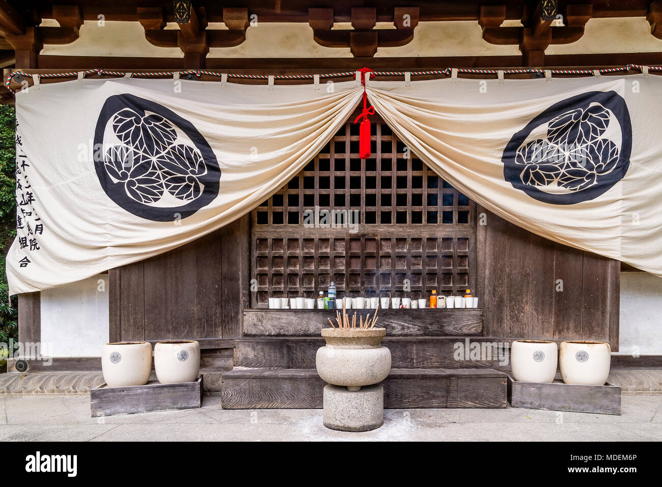 Stone pot with incense sticks and row of votive offerings in the Chion