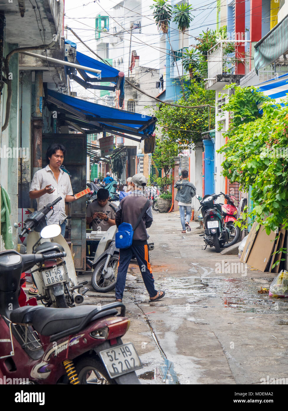 Vietnamese men going about their daily life in a narrow lane in Ho Chi Minh City, Vietnam. Stock Photo