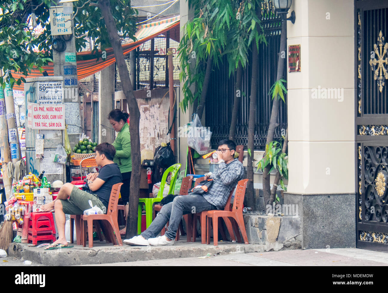 Two men sitting on plastic chairs drinking at a roadside juice bar in