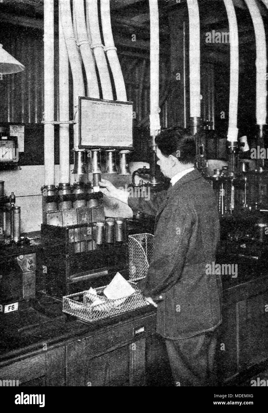 Operating pneumatic tubes machine system  sending messages to newspaper offices Central telegraph office London 1930's Stock Photo