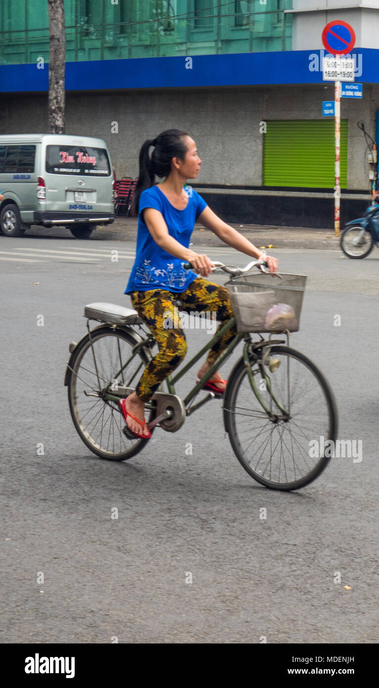 A Vietnamese woman with long hair in a ponytail riding a vintage ...