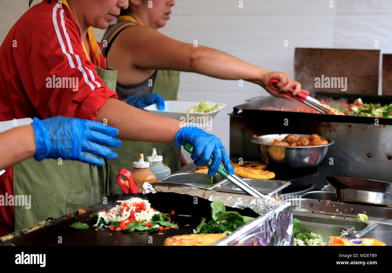 Women observing hygiene laws serving ethnic food at a street festival