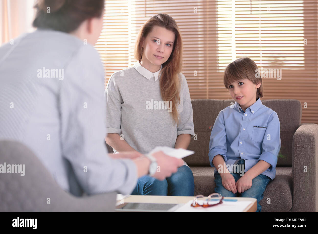 Kid with ADHD and his mother listening to a counselor during meeting in the office Stock Photo