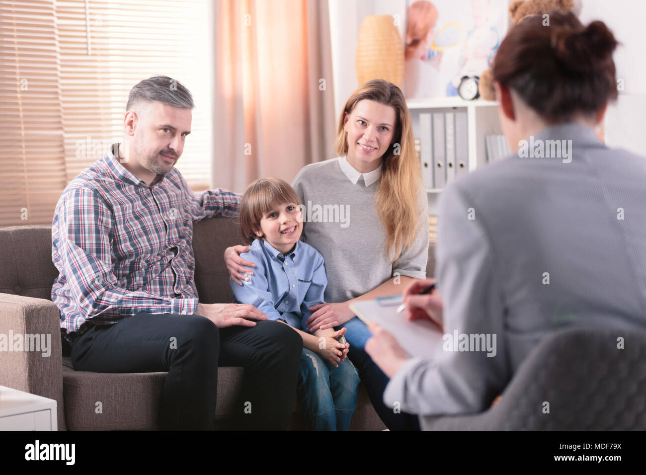 Smiling son with his happy parents during a consultation with advisor Stock Photo