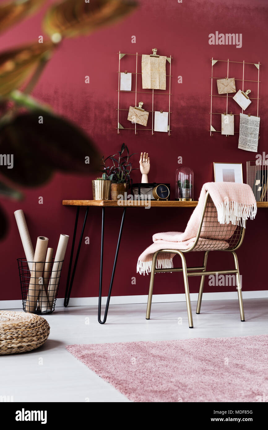 Blanket on gold chair at wooden desk with clock in feminine, pink home