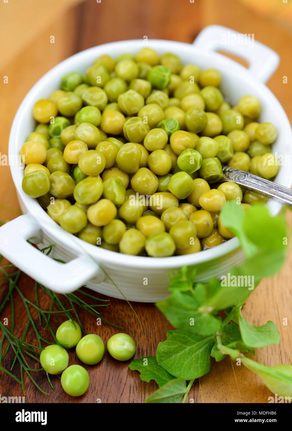 Boiled young green peas in a white bowl. Stock Photo