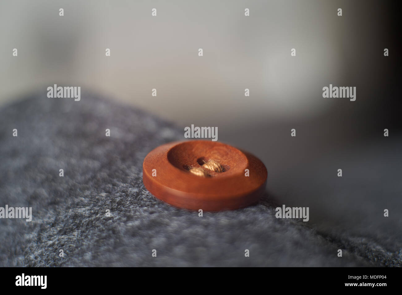 Sewn button playing with light, shadow, reflection and surfaces, selective focus. Stock Photo