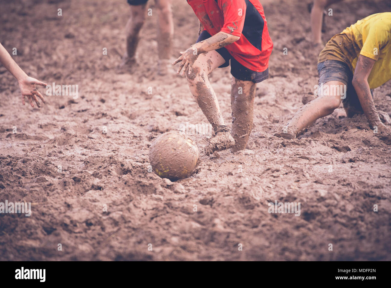 Two boys playing football in the mud with their friends Stock Photo Alamy