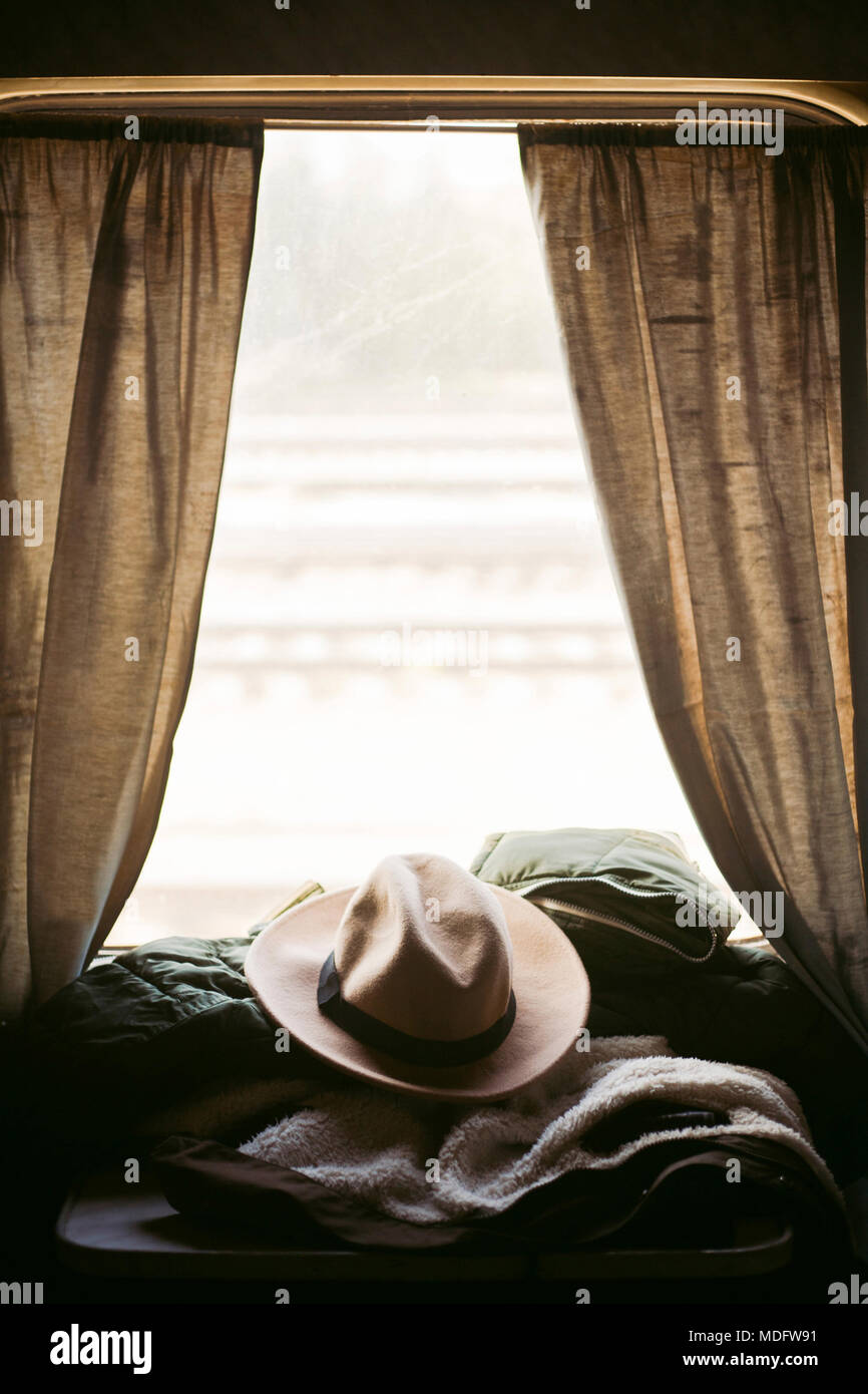Man's hat, coat and sleeping bag on a table in a train carriage Stock Photo