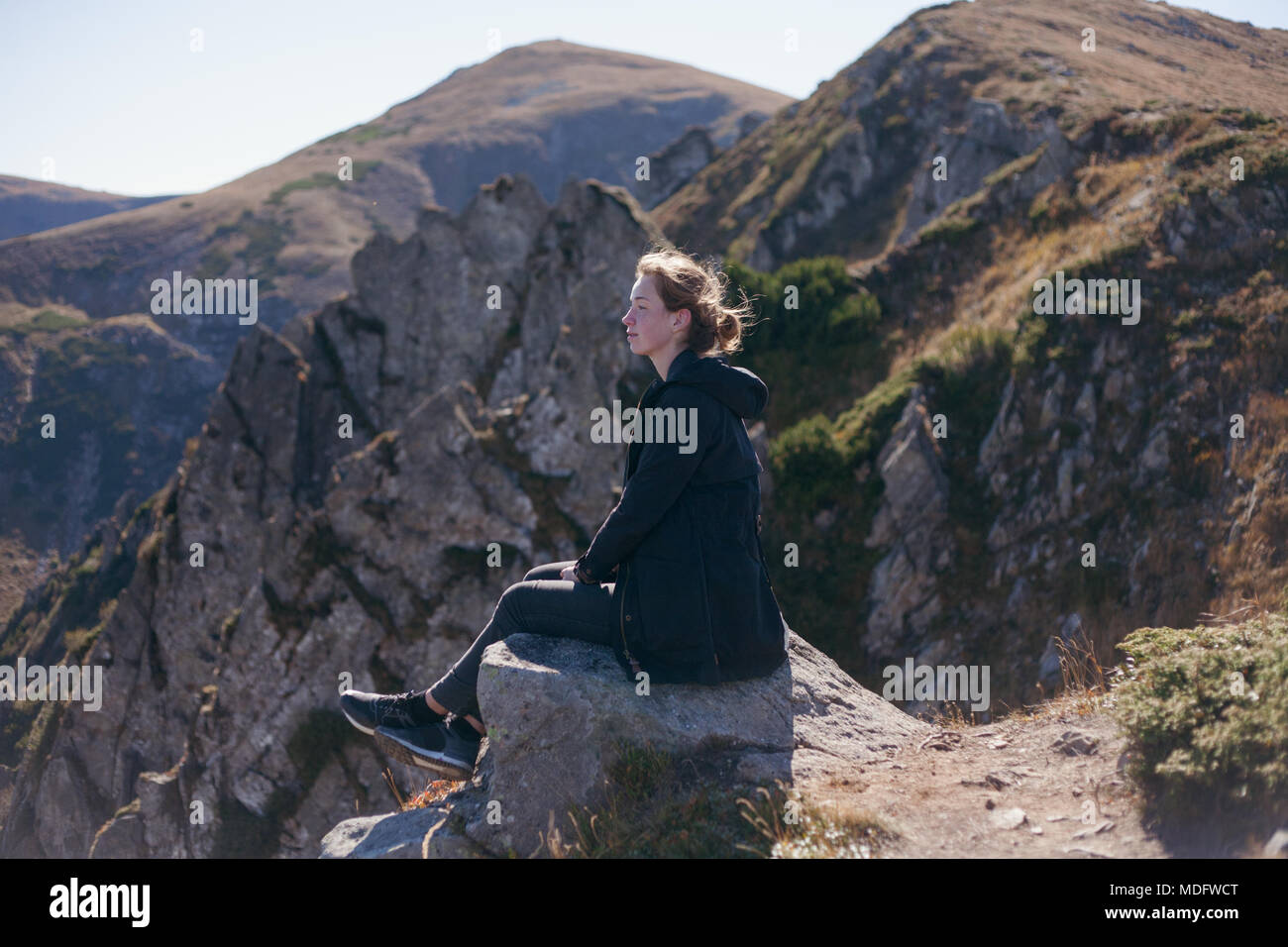 Woman sitting on a cliff looking at mountain view, Ukraine Stock Photo