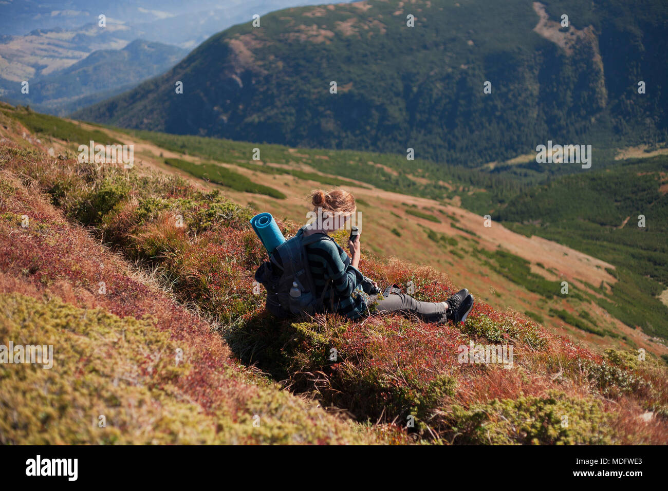 Woman sitting on mountain slope taking a photo, Ukraine Stock Photo