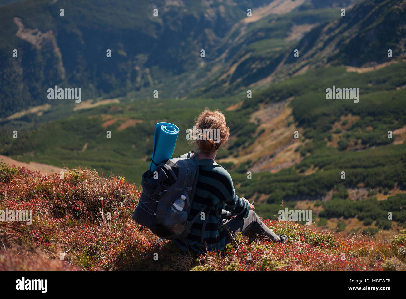 Woman sitting on mountain slope taking a photo, Ukraine Stock Photo