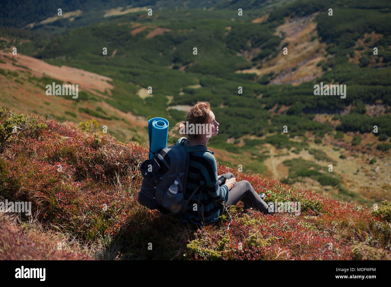 Woman sitting on mountain slope looking at view, Ukraine Stock Photo