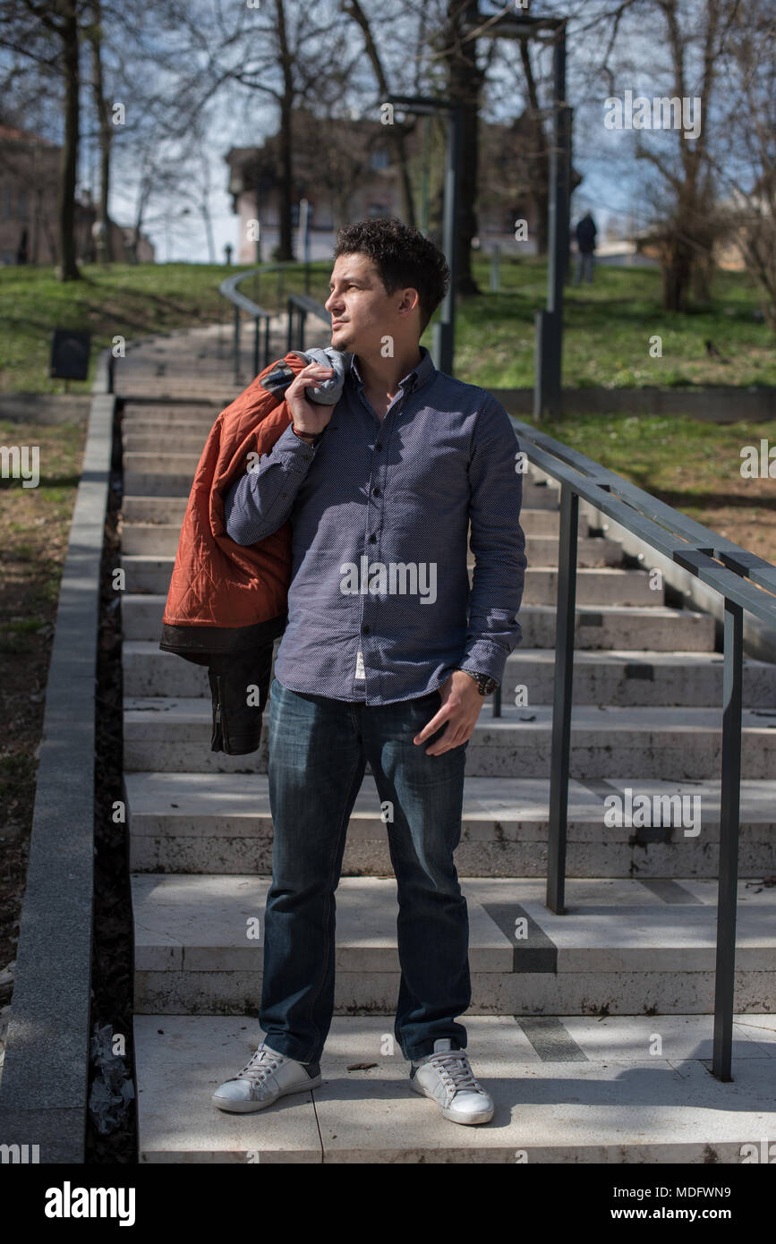Man standing on steps with a jacket over his shoulder Stock Photo