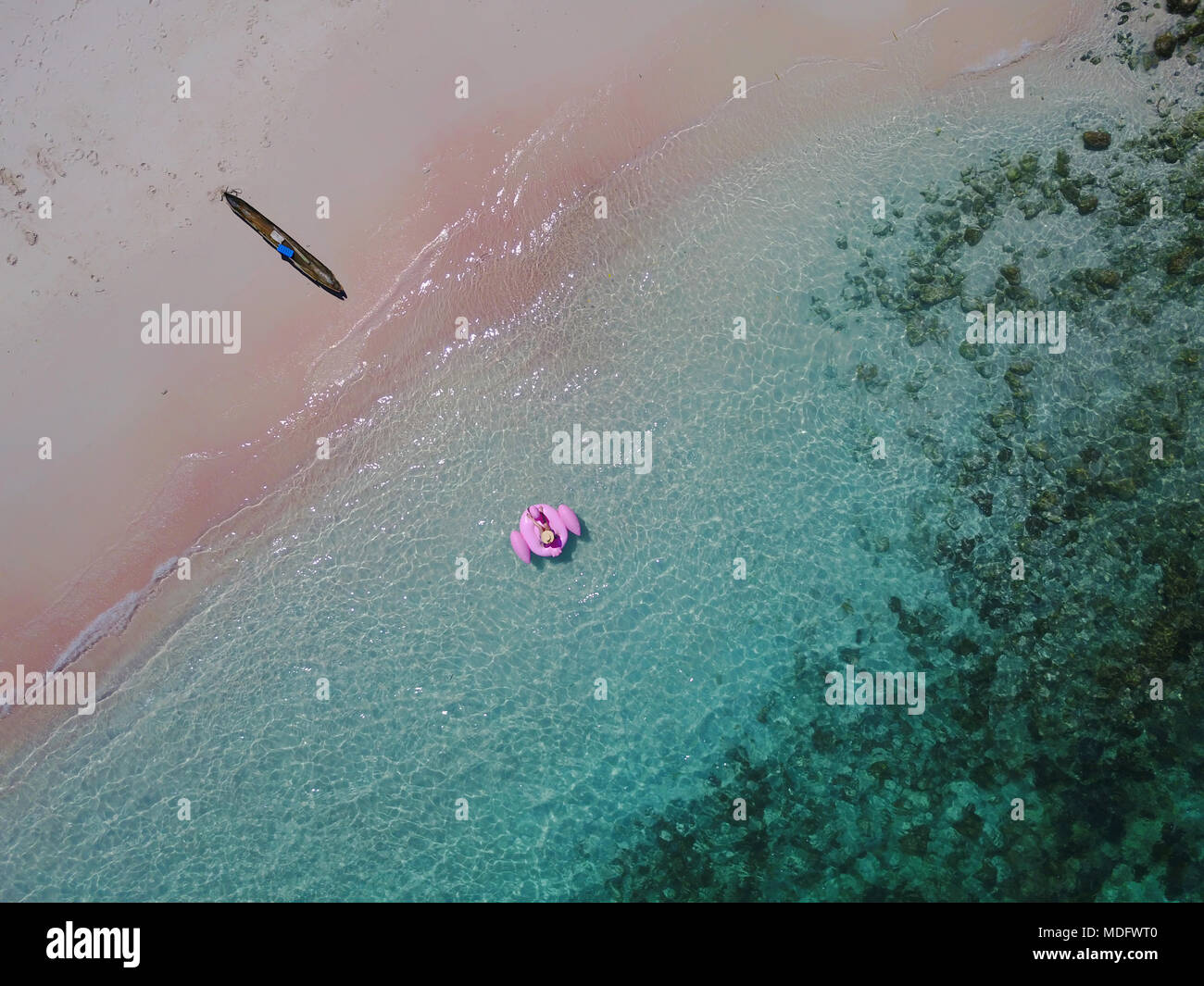 Aerial view of a woman on a pink inflatable flamingo float, Pink Beach, East Nusa Tenggara, Indonesia Stock Photo