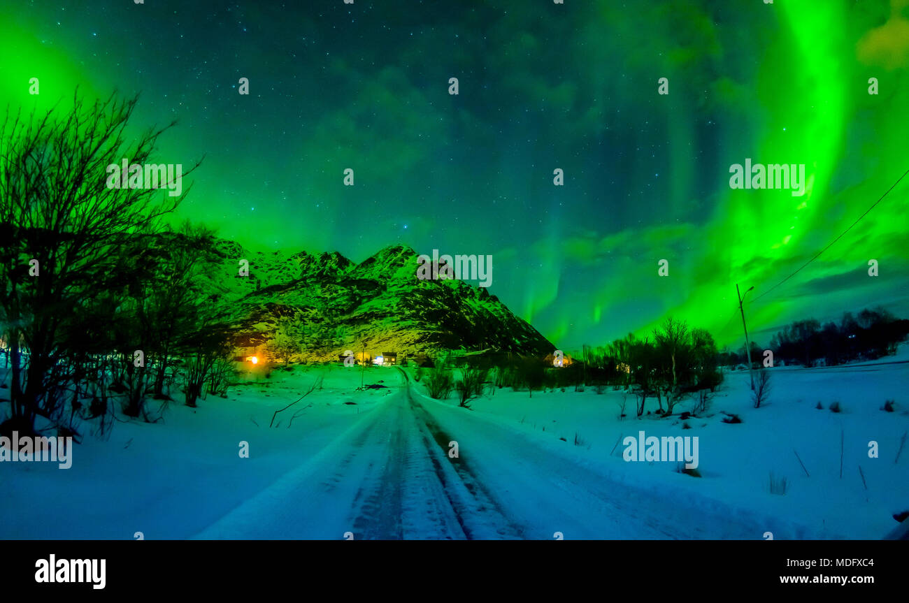 Northern lights shine bright and beautiful above sharp peaks and lakes of Lofoten mountains Stock Photo