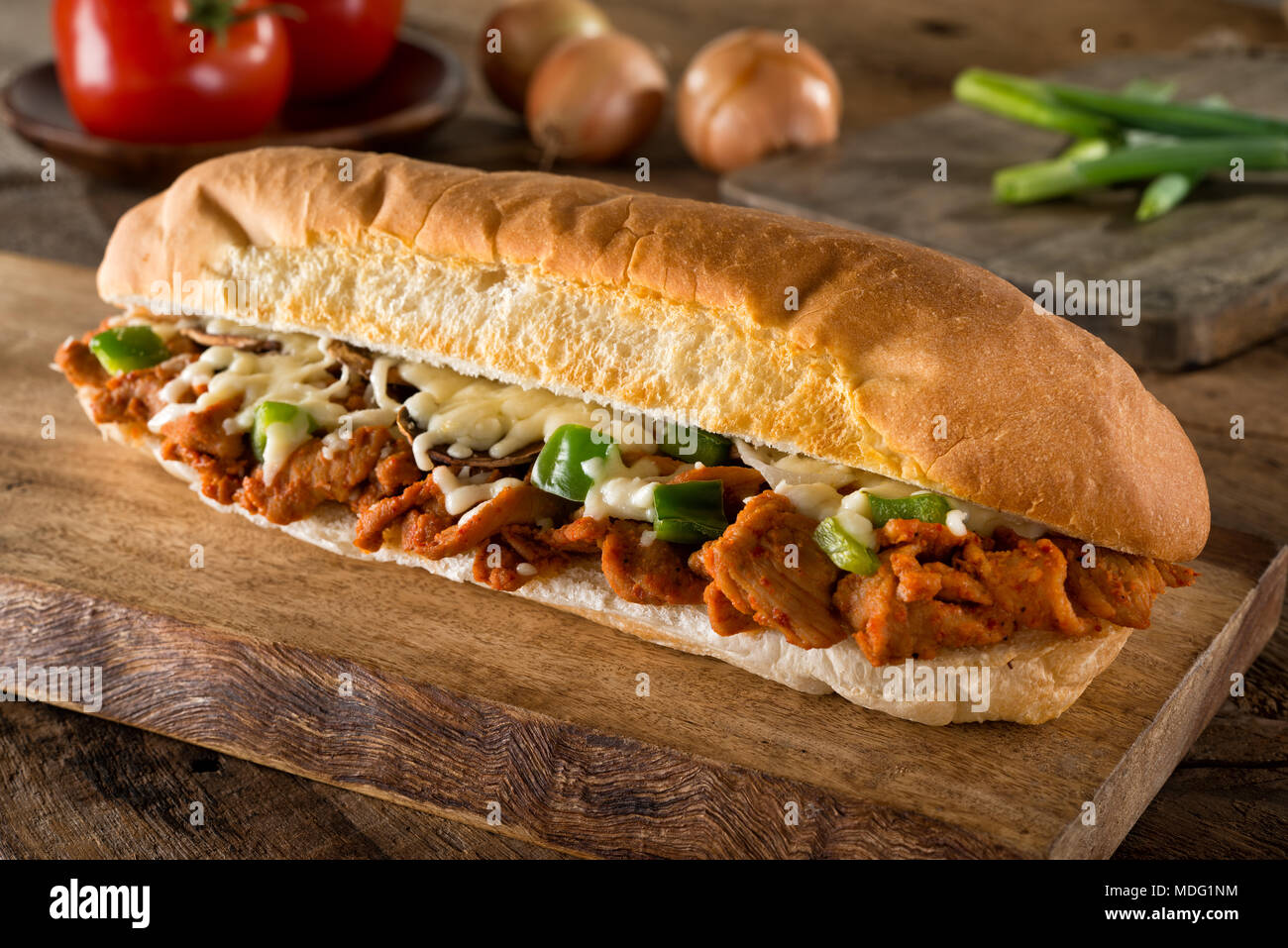 A delicious spicy barbecue pork submarine sandwich on a rustic wood table top. Stock Photo