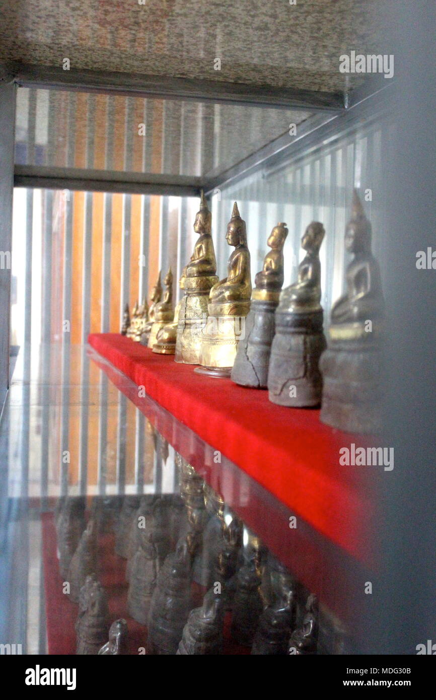 Solid gold and silver Buddha statues seen through security bars at the Lao National Museum