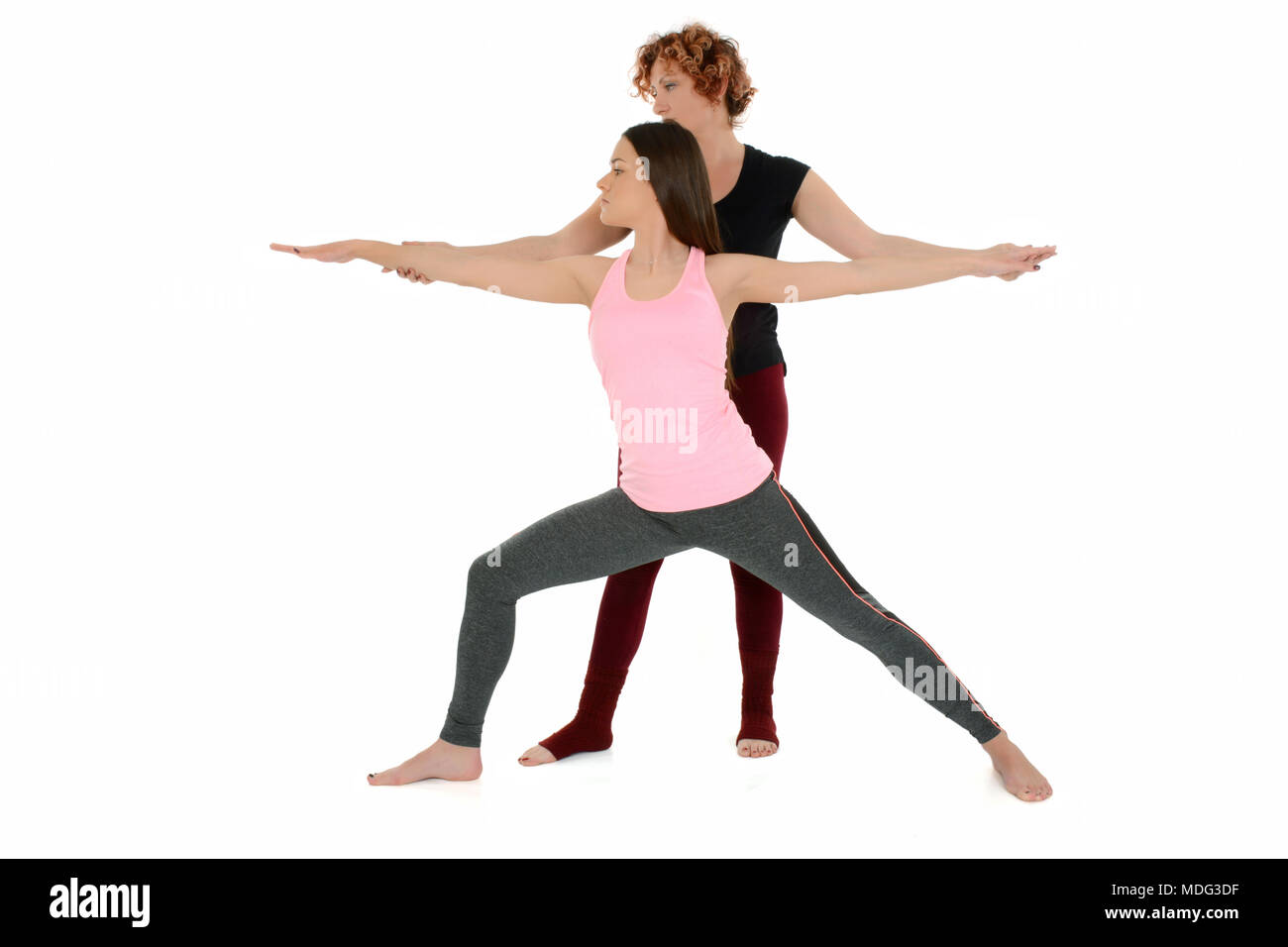 Yoga teacher shows how to put a young white girl in the Yoga position Warrior Pose, on sanskrit Virabradasana. Stock Photo