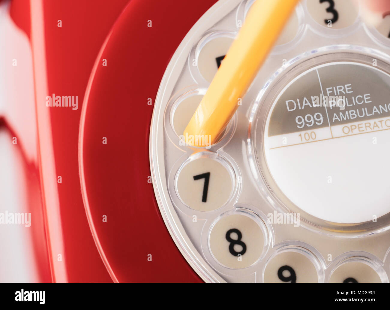 Close up of retro red 1960s to 1970s telephone with yellow pencil poised to dial number. Stock Photo
