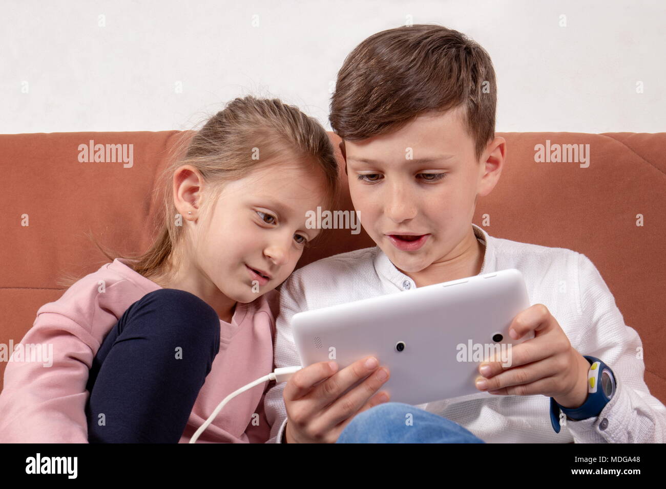 Girl and boy, sister and brother playing together with digital tablet Stock Photo