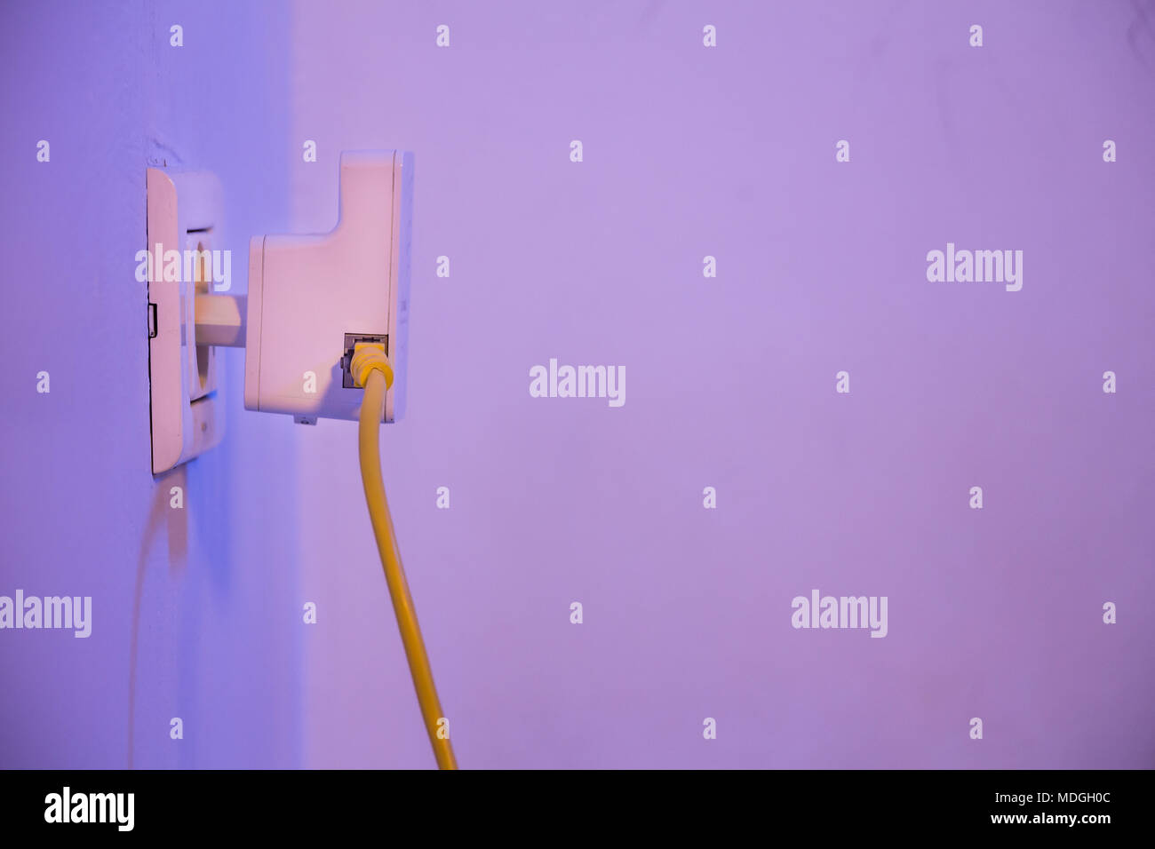WiFi extender in electrical socket on the wall with cable