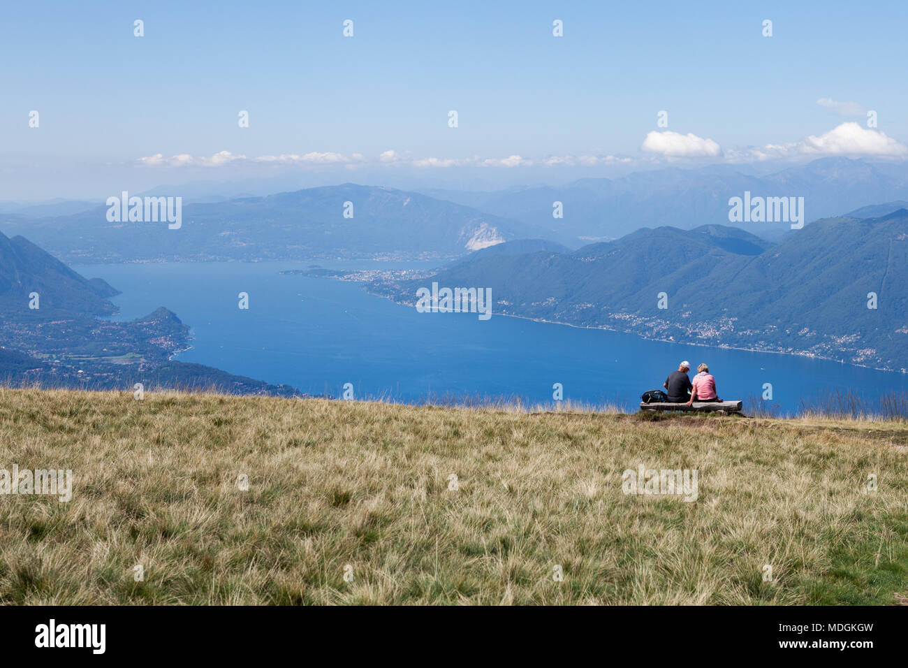 Two tourists contemplating the beautiful view of Lago Maggiore (Lake Maggiore) from the top of Monte Lema (Mount Lema).  Veddasca, Italy Stock Photo