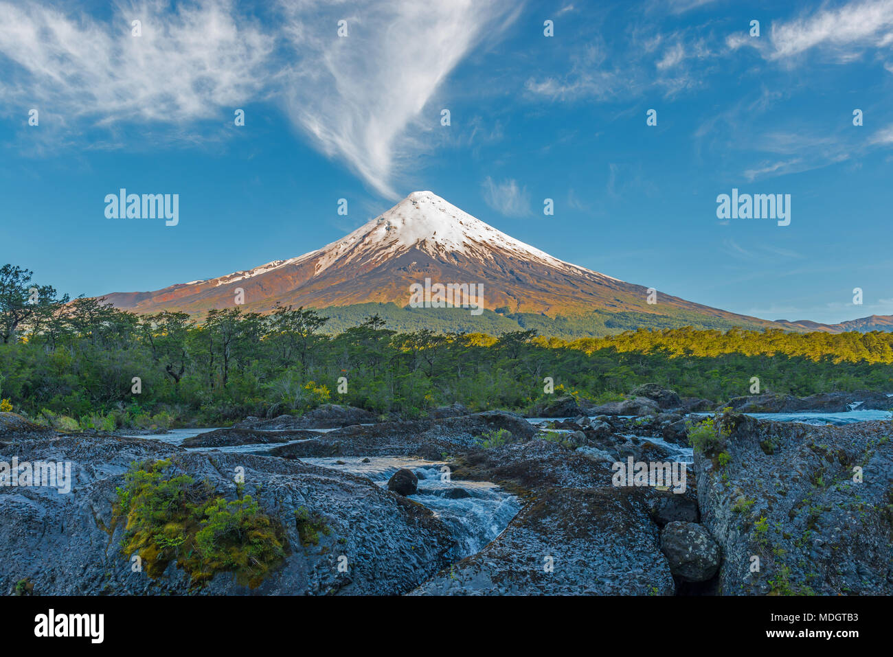 The majestic Osorno volcano at sunrise by the Petrohue waterfalls in the lake district of Chile near Puerto Varas, South America. Stock Photo