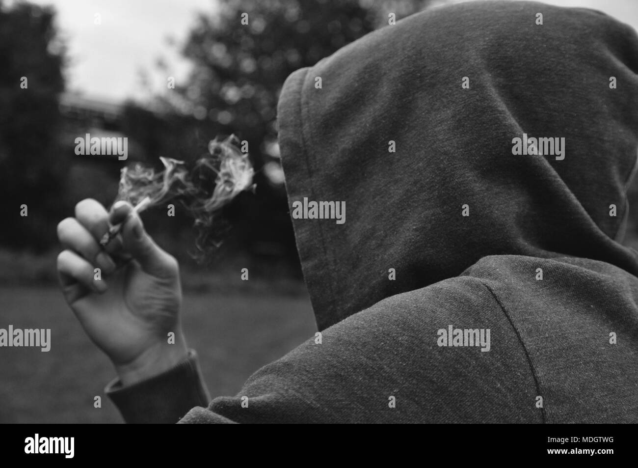 Mysterious faceless person smoking wearing a hood Stock Photo