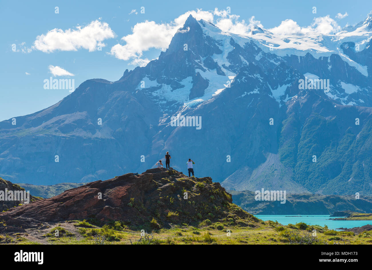 Three tourists enjoying the view upon the Torres del Paine massif while on a trekking inside the Torres del Paine national park, Patagonia, Chile. Stock Photo