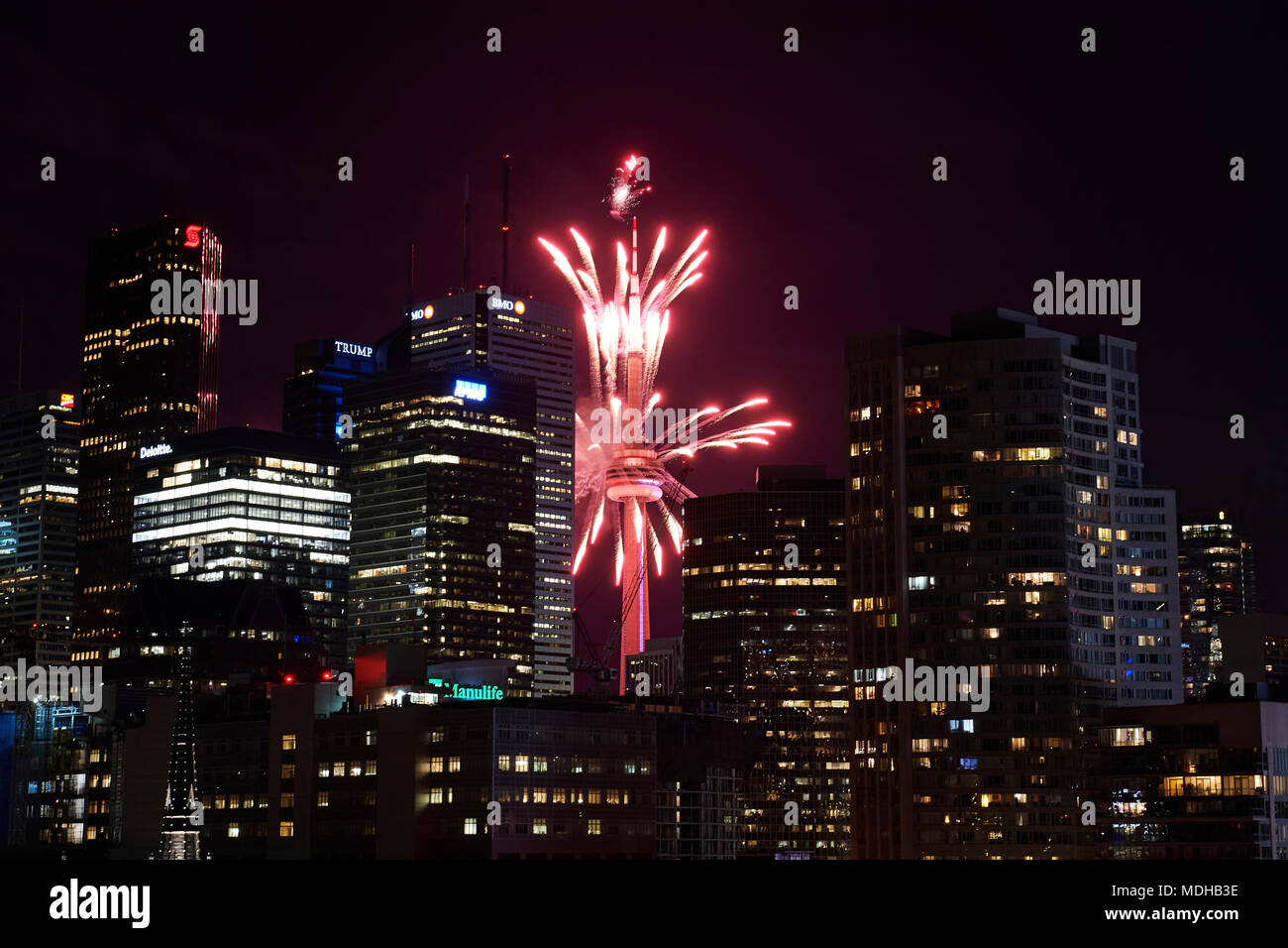 Red fireworks in the night sky in front of the CN tower; Toronto
