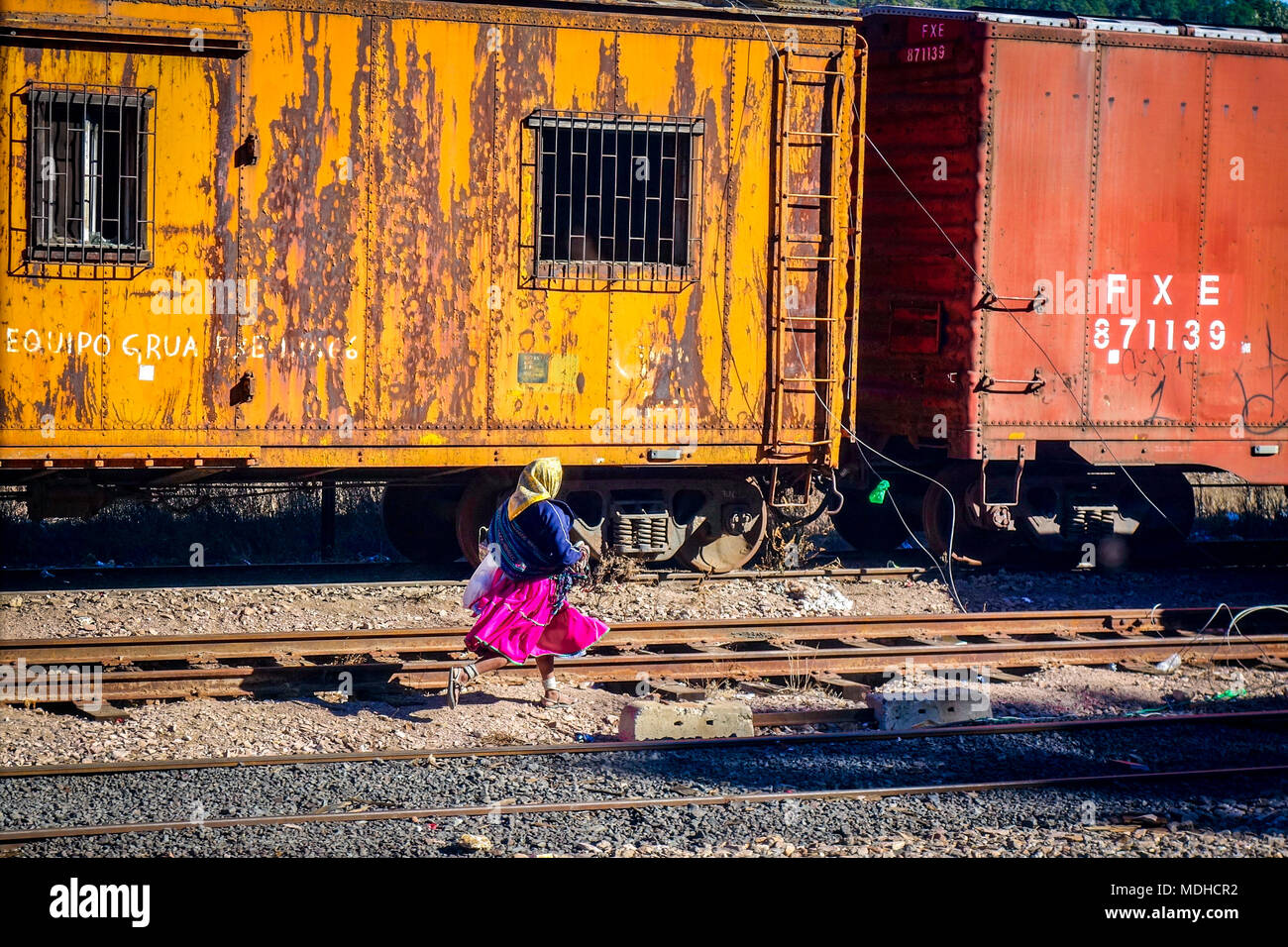 CREEL, MEXICO-Jan 2016: A native Raramuri woman in bright clothing runs across railway tracks while waiting for the El Chepe Copper Canyon train at Cr Stock Photo