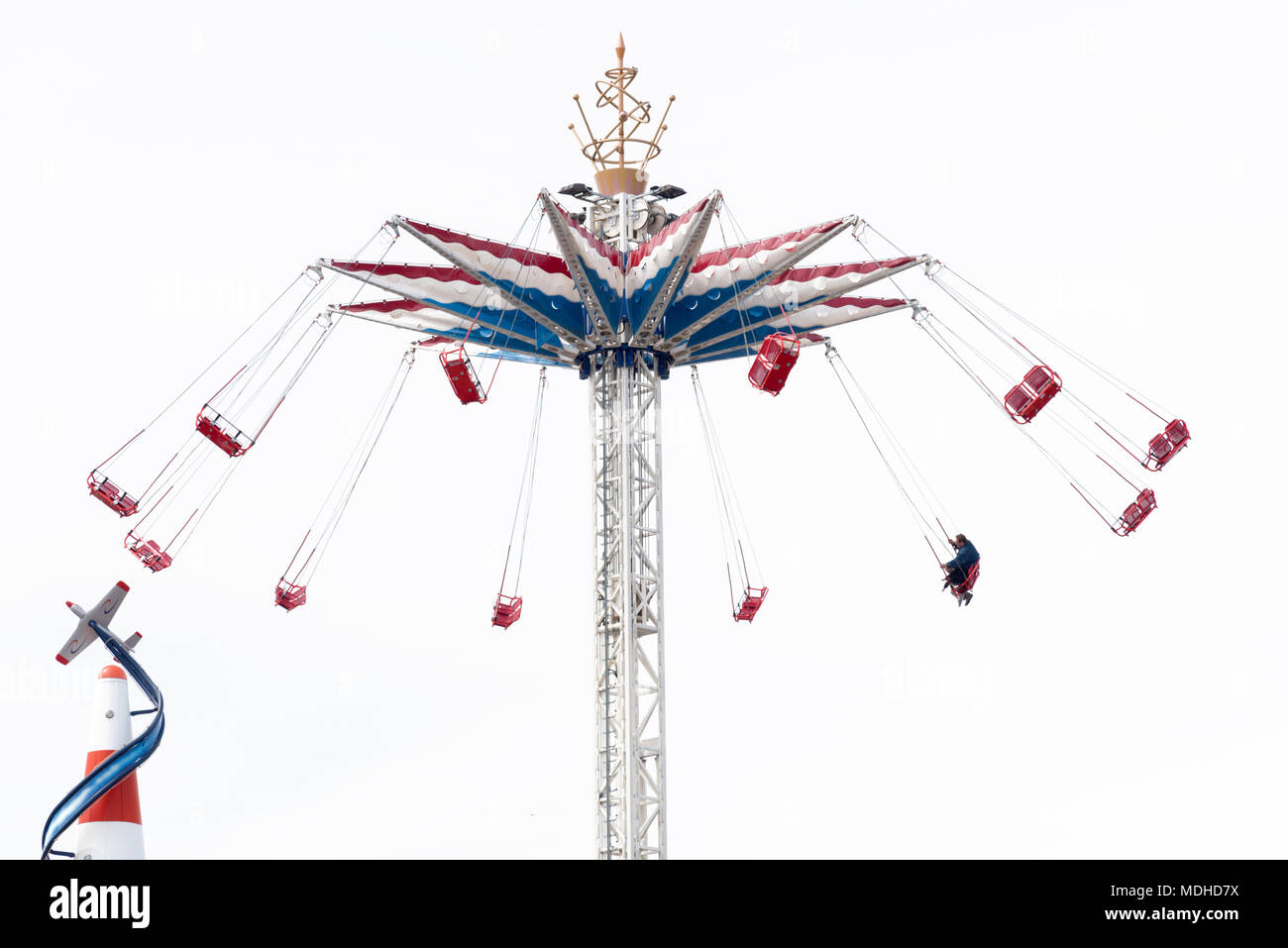 Coney Island Luna Park located in Brooklyn New York under overcast bright white sky, swing thrill ride with only one seat taken. Stock Photo