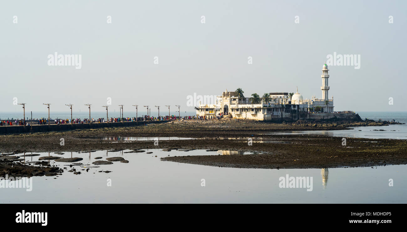 Tourists on a road leading to a building and tower along the coast, Arabian Sea; Mumbai, Maharashtra, India Stock Photo