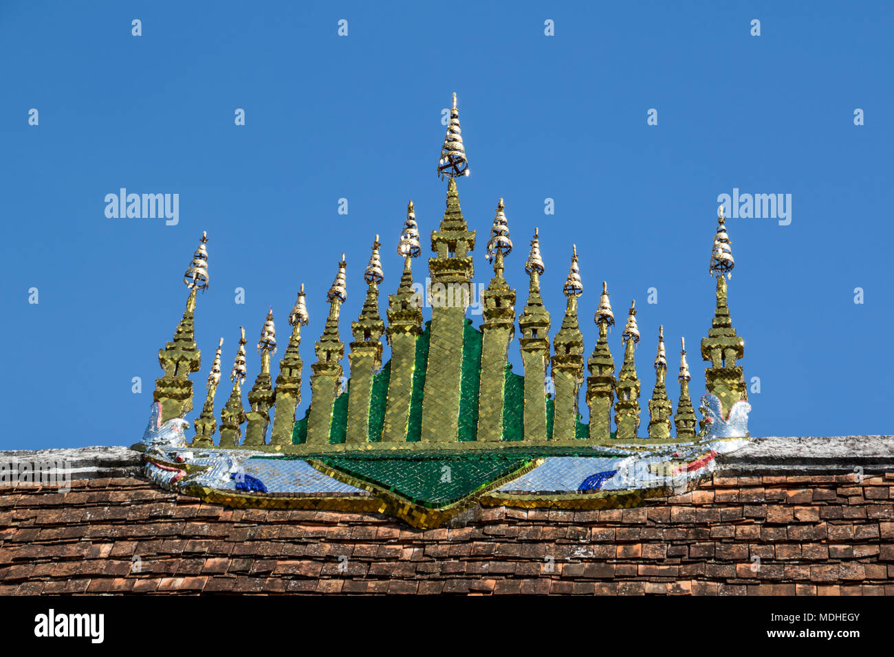 Gilded ornamental element consisting of 17 miniature stupas covered by 7 tiered parasols atop the roof of the sim (congregation hall) of Wat Xieng ... Stock Photo