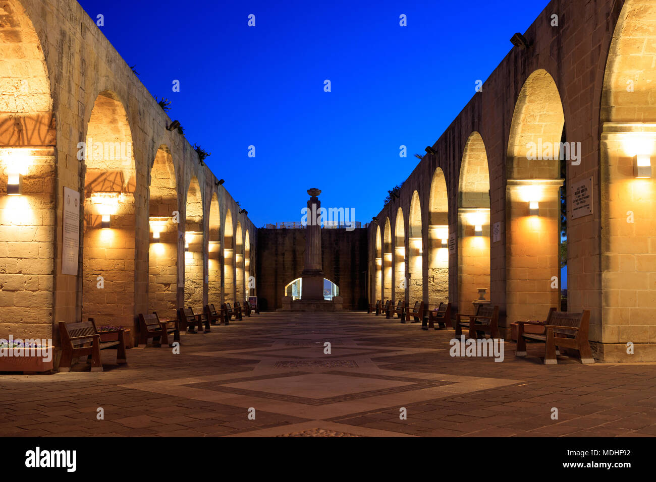 Valletta, Malta, Upper Barrakka Gardens. Illuminated stone arches in the evening, clear dark blue sky. Stock Photo
