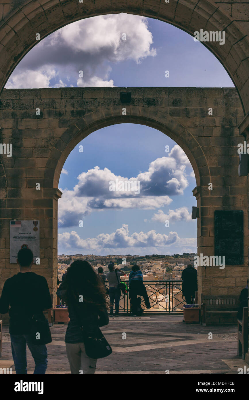 Valletta, Malta, Upper Barrakka Gardens. Terrace with stone arches and a view to the Grand harbor, cloudy blue sky. Stock Photo