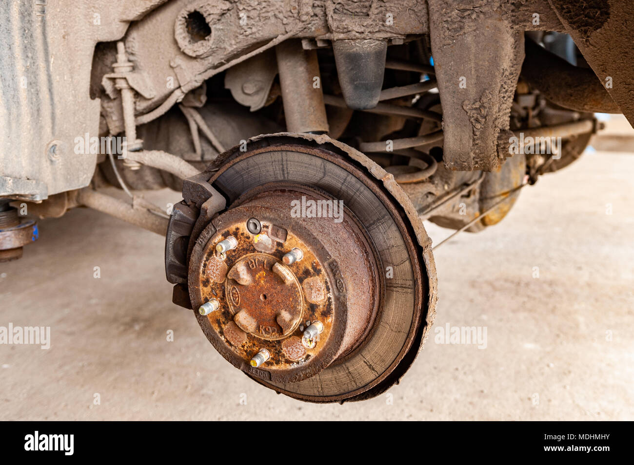 Wheel hub, brake and suspension assembly on a 2004 Kia Sorento jacked up inside a garage Stock Photo