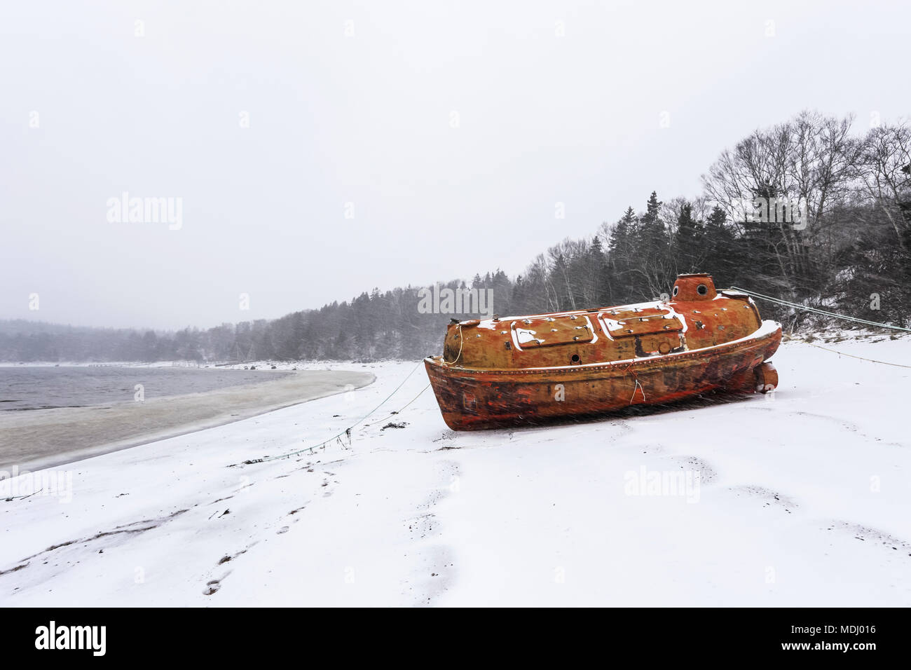 An old emergency life-boat safety vessel on the snowy shore in Sandy Cove harbour; Sandy Cove, Nova Scotia, Canada Stock Photo