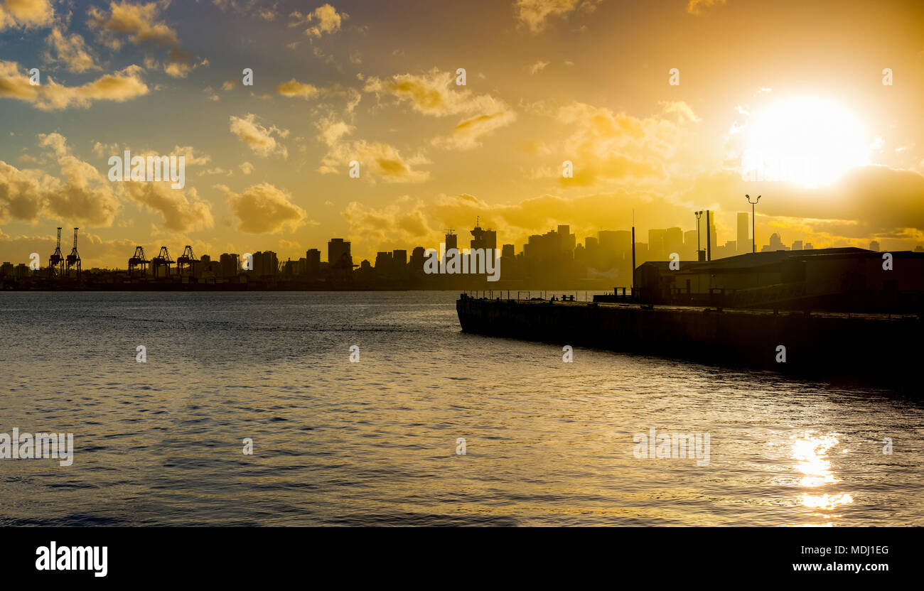 Skyline of Vancouver and the coastline with a golden sky at sunrise; Vancouver, British Columbia, Canada Stock Photo