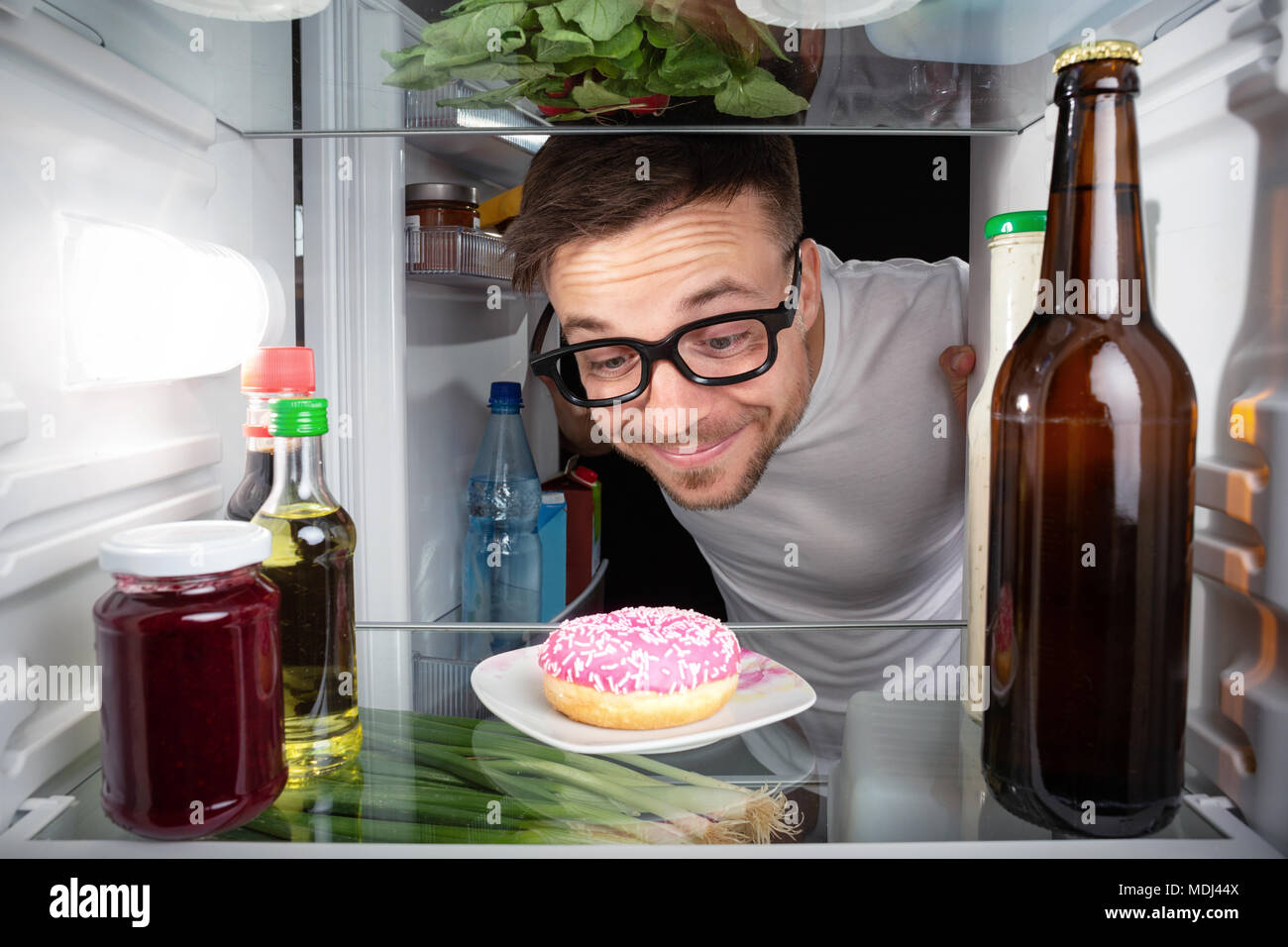 Nerd happy about a donut in the fridge Stock Photo