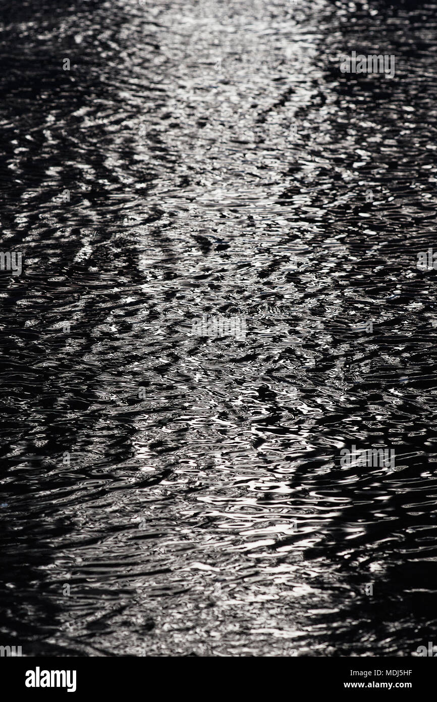Dark contrast water surface with ripples and reflections texture ...