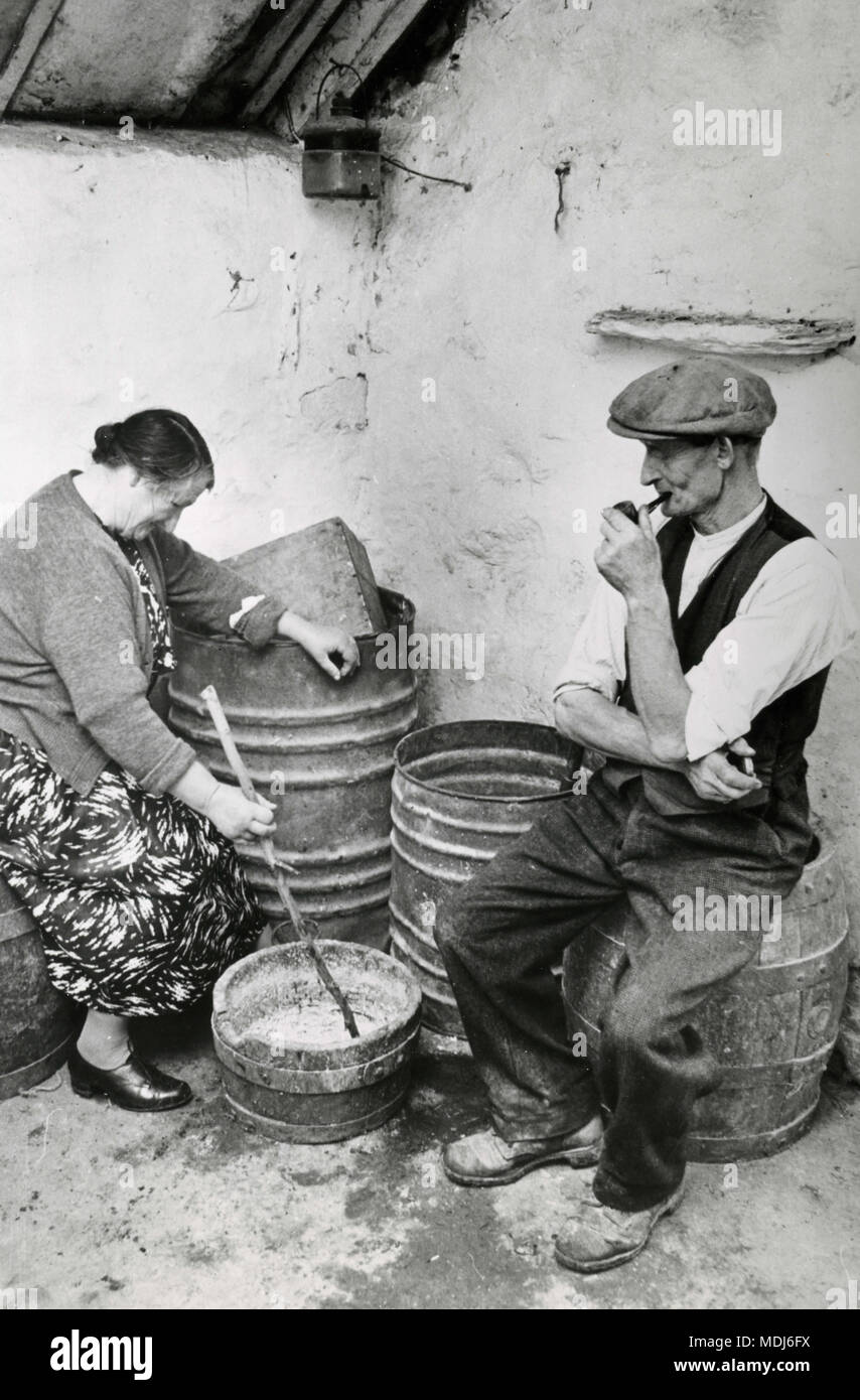 James Kennedy and his sister Mary Ryan preparing food for chicken in Kennedy's family house, 1960s Stock Photo