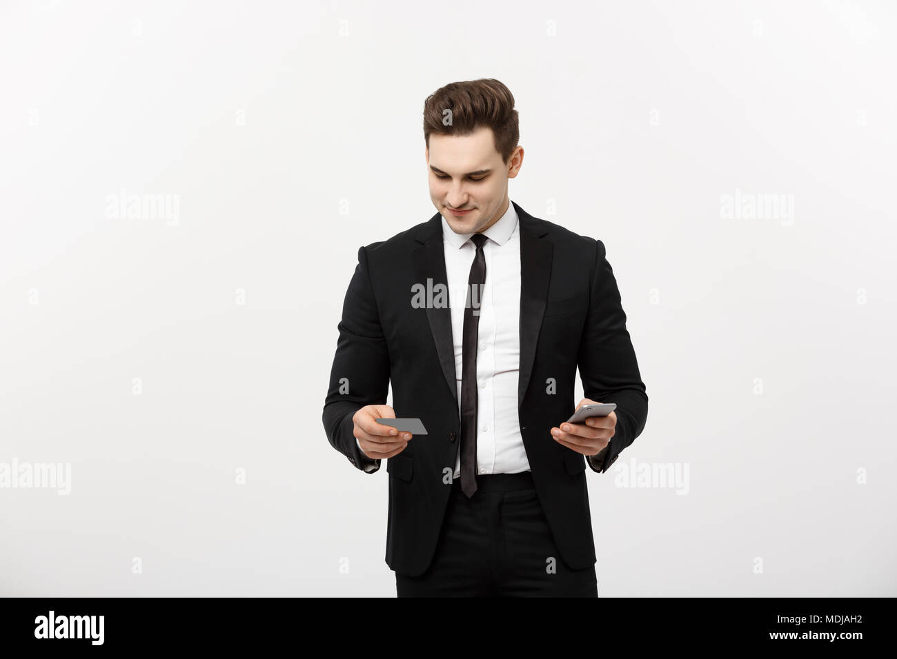 Portrait of happy young businessman in smart black suit standing ...