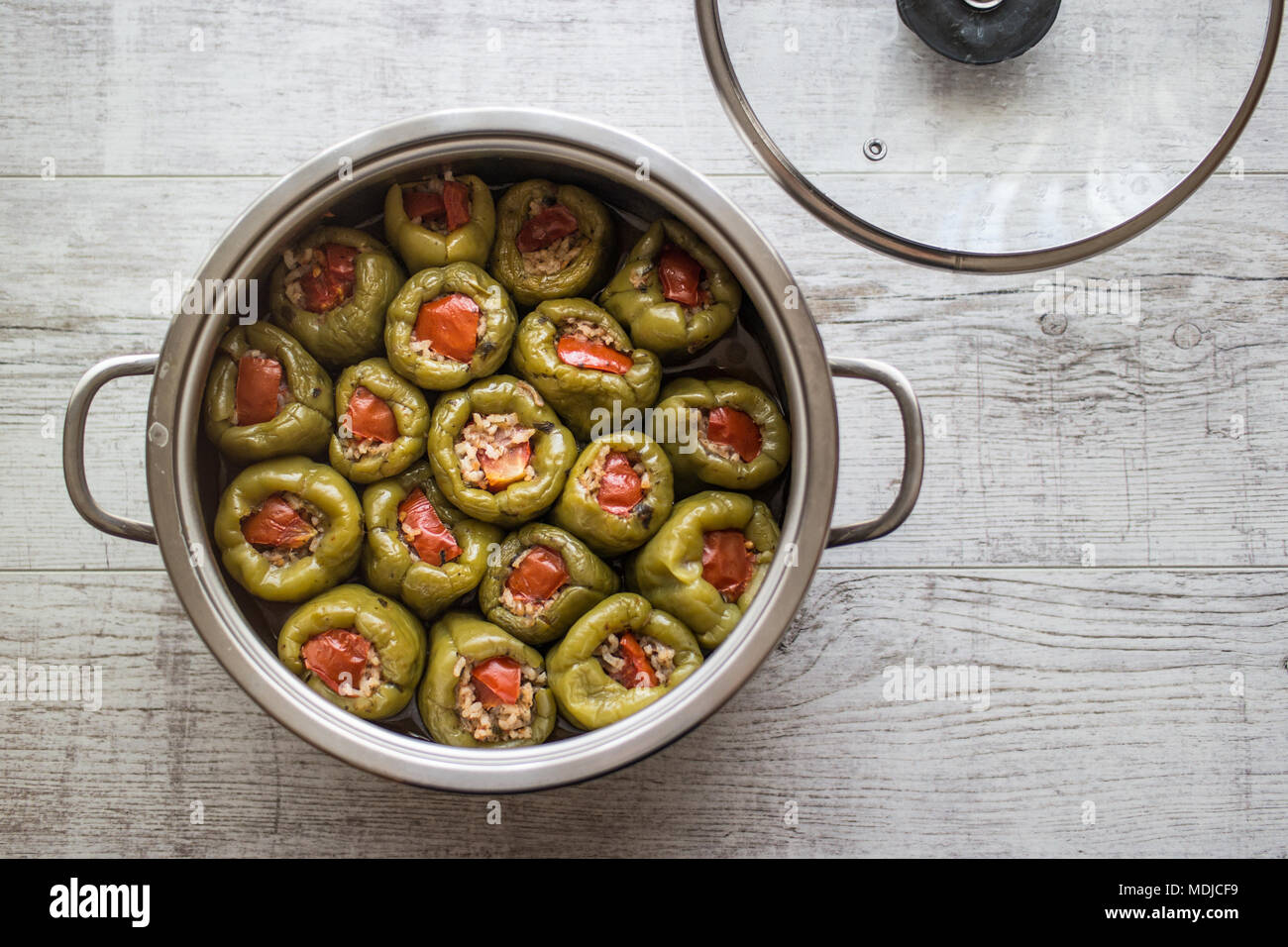 Biber Dolmasi / Turkish Stuffed Peppers in a pan on a white wooden surface. Stock Photo