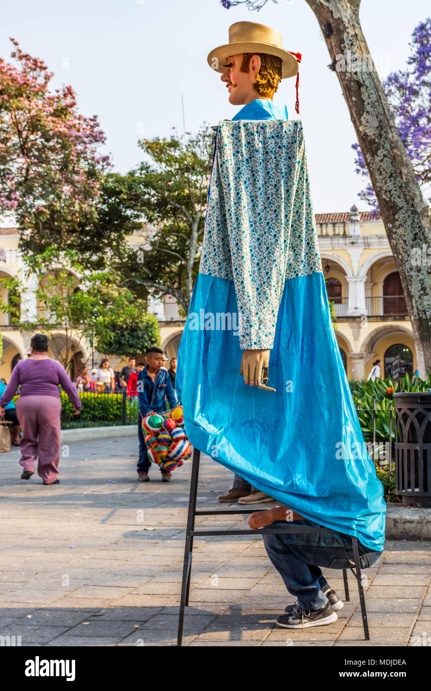 Antigua, Guatemala -  March 9, 2018: Man rests inside traditional giant folk dancing puppet called a gigante in central plaza Stock Photo
