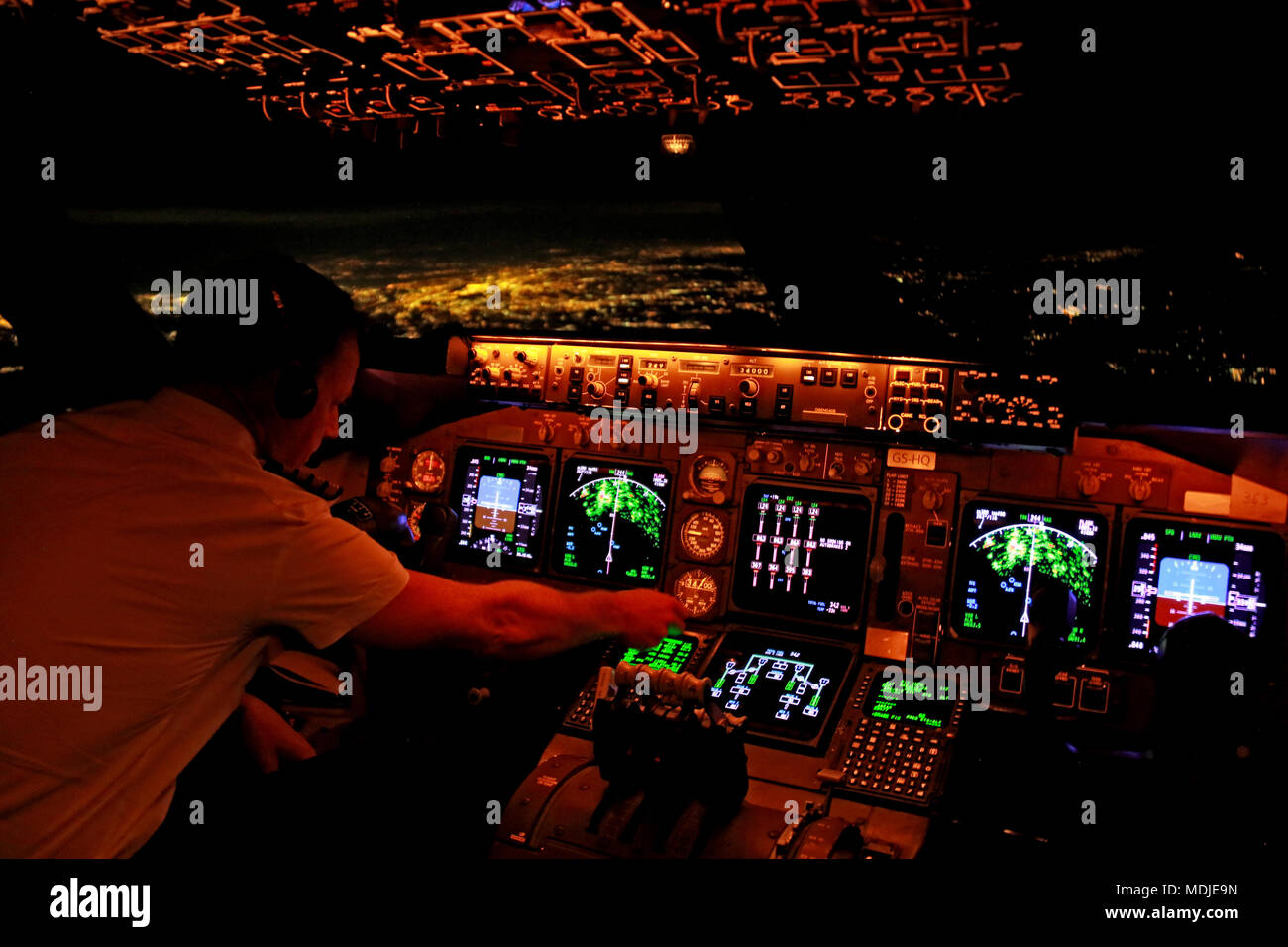 A pilot preparing the FMS on the flight deck of a Boeing 747-400 overhead NYC (in the background) for a landing at Atlanta Hartsfield-Jackson Stock Photo